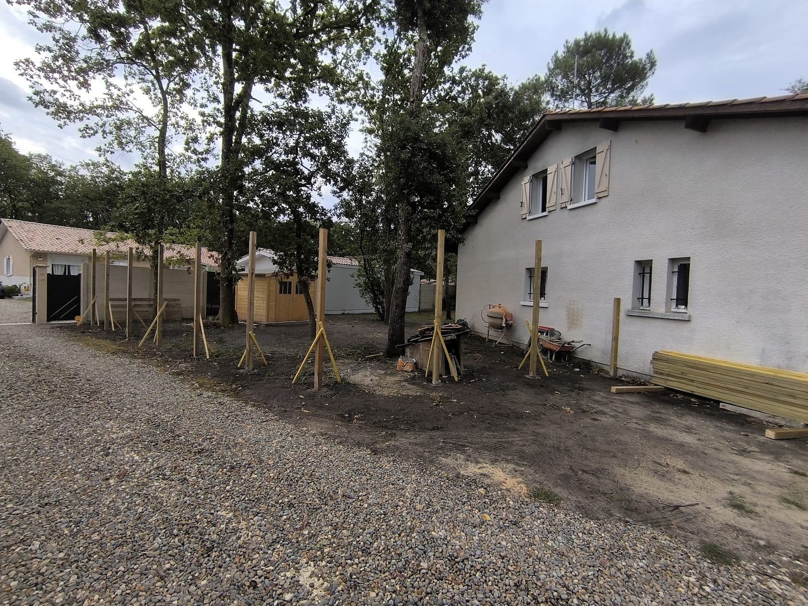 Rangée de poteaux bois scellés et maintenus par des liteaux le long d'un jardin à Gujan-Mestras